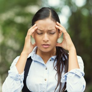 Closeup portrait unhappy young business woman hands on head stressed bothered by mistake having bad headache migraine isolated outdoor park background. Negative human emotion facial expression feeling