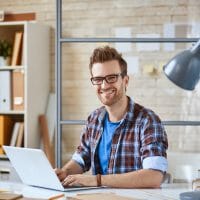 Portrait of a positive guy working with laptop