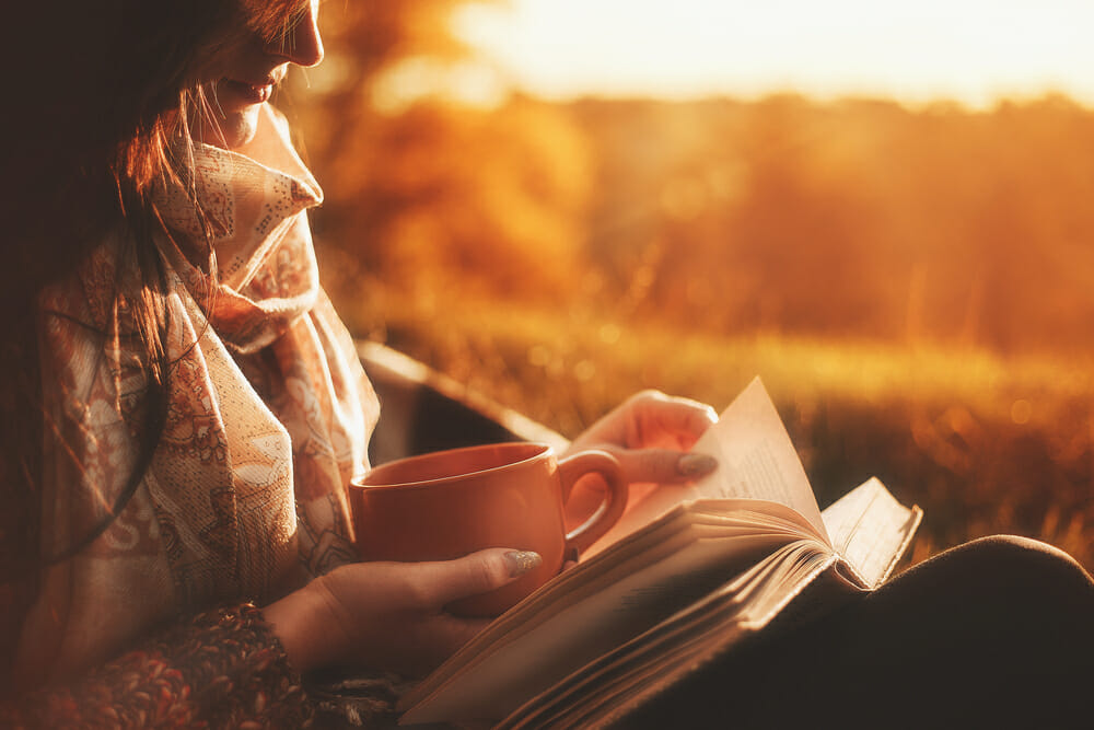 woman reading a book outside with the sun on her