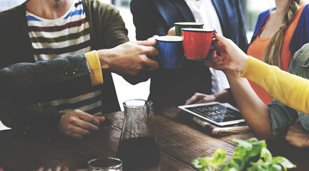 Group of people clinking coffee mugs