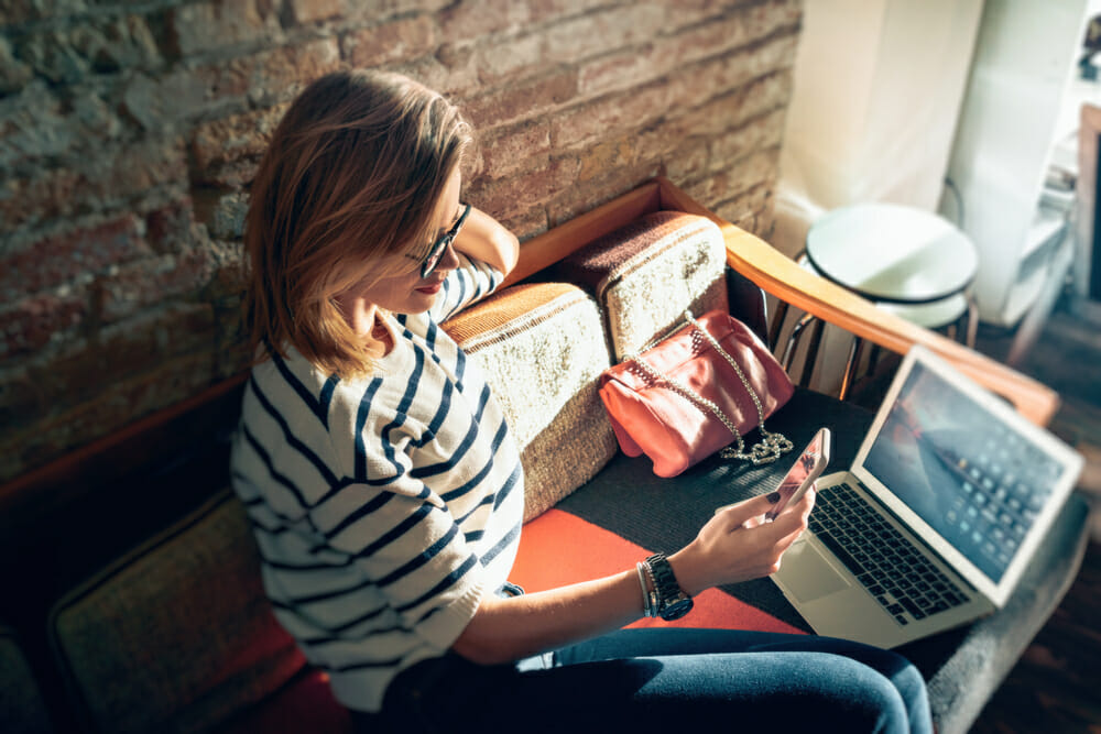 woman sitting on a couch with her laptop and phone