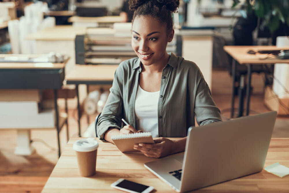 Woman sitting at a desk with a laptop and notepad