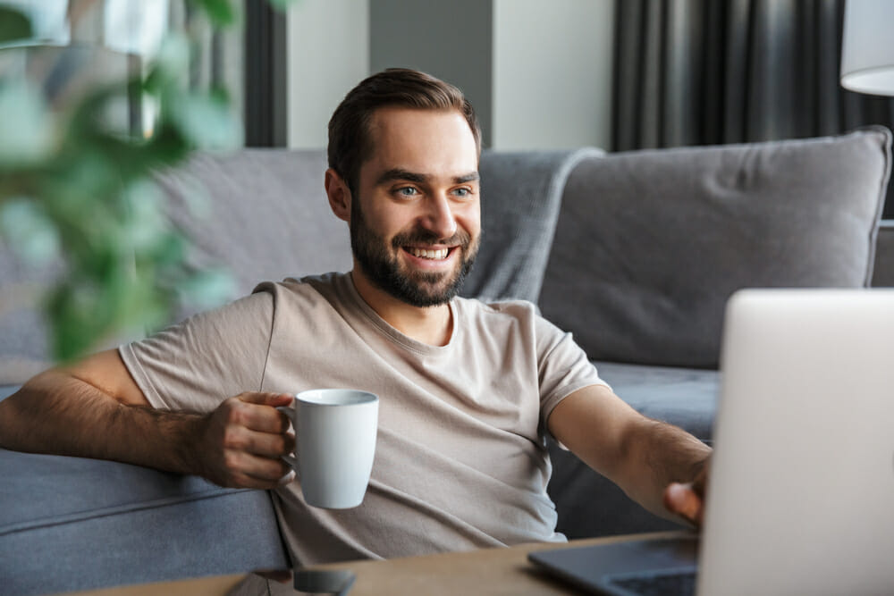 Man sitting in front of his laptop holding a mug