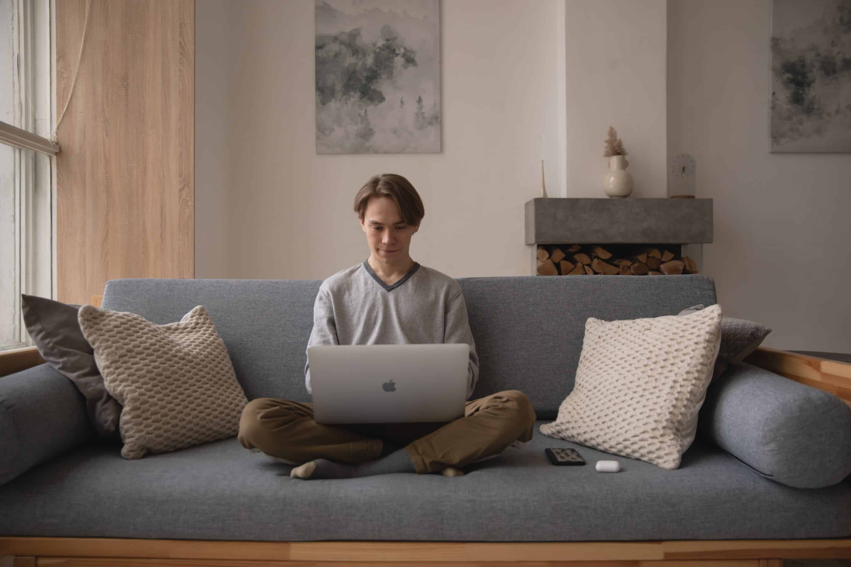 Man sitting on a couch working on his laptop