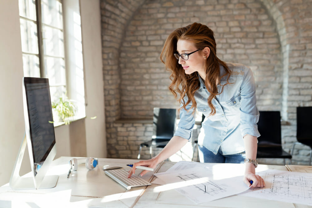 Woman standing at a table looking at her computer