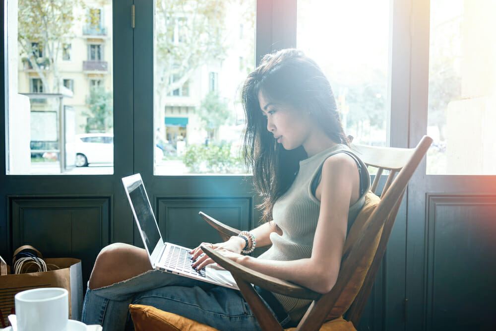 Woman sitting in a chair typing on her laptop.