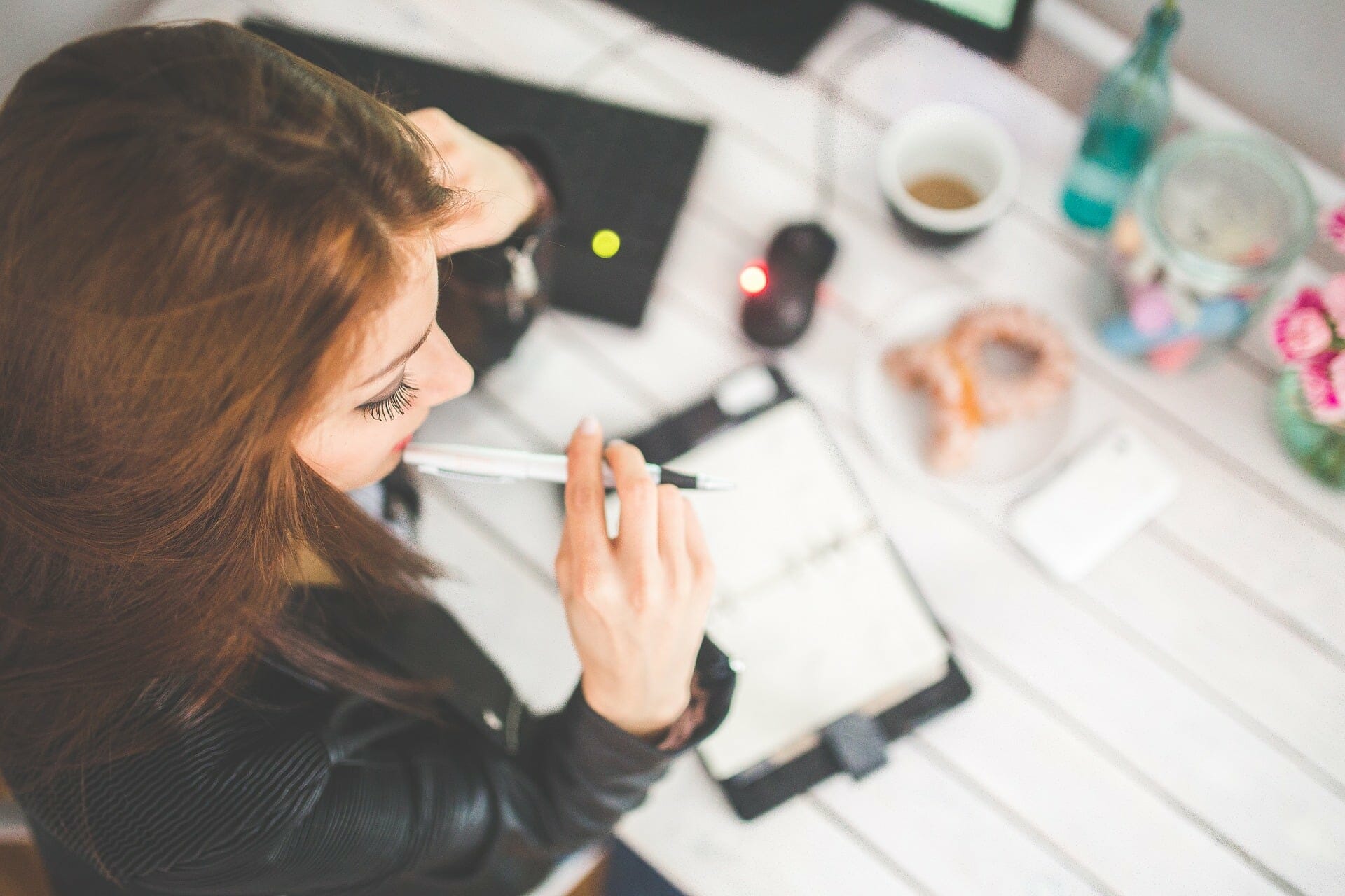 Woman in suit bites pen, looks at calendar