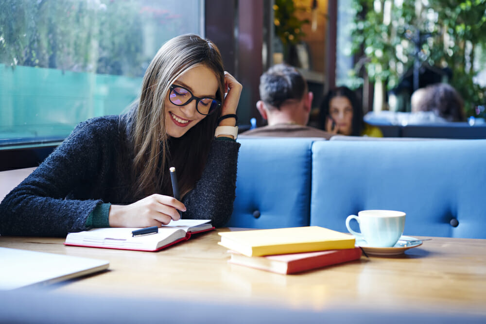 Woman writing in a notebook in a cafe