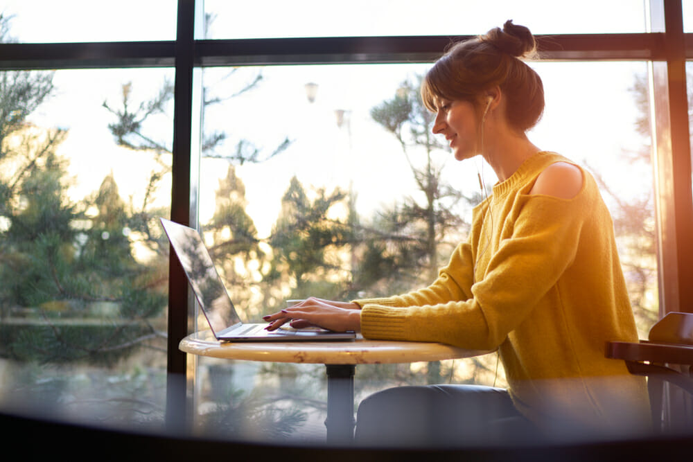 woman typing on a computer in front of a window