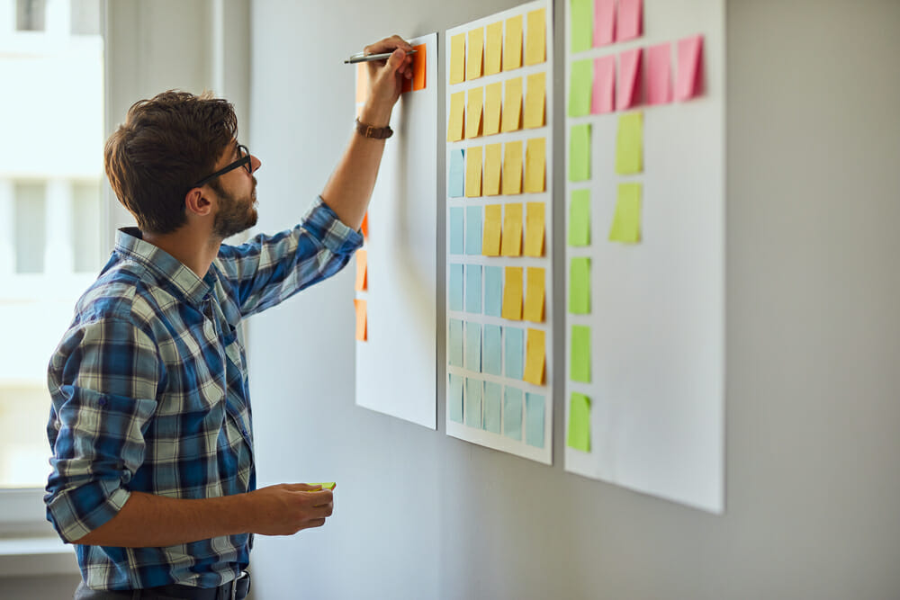 Man putting post it notes on the wall