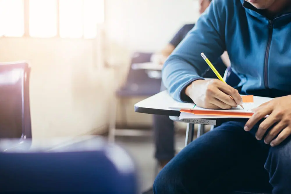 Man sitting at a desk taking a quiz with a pencil