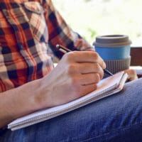 Person writing with a cup of coffee