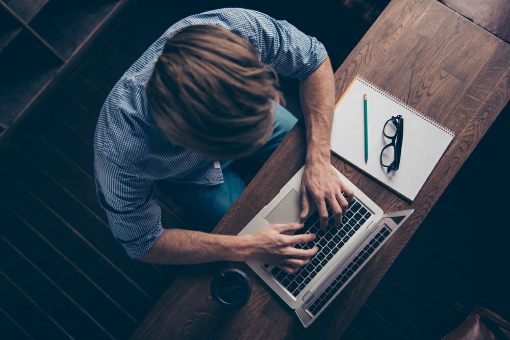 View of person writing on a computer from above