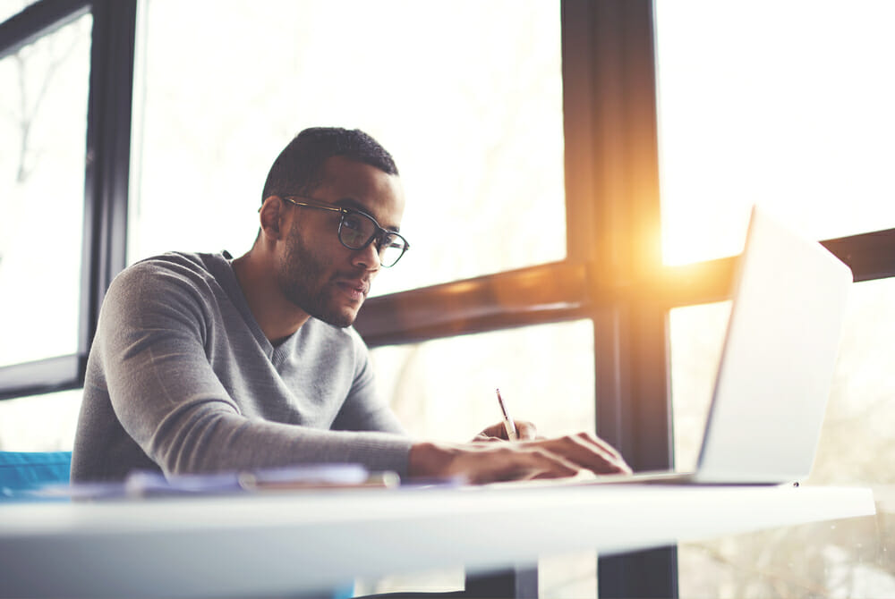 Man sitting in front of his laptop near big windows