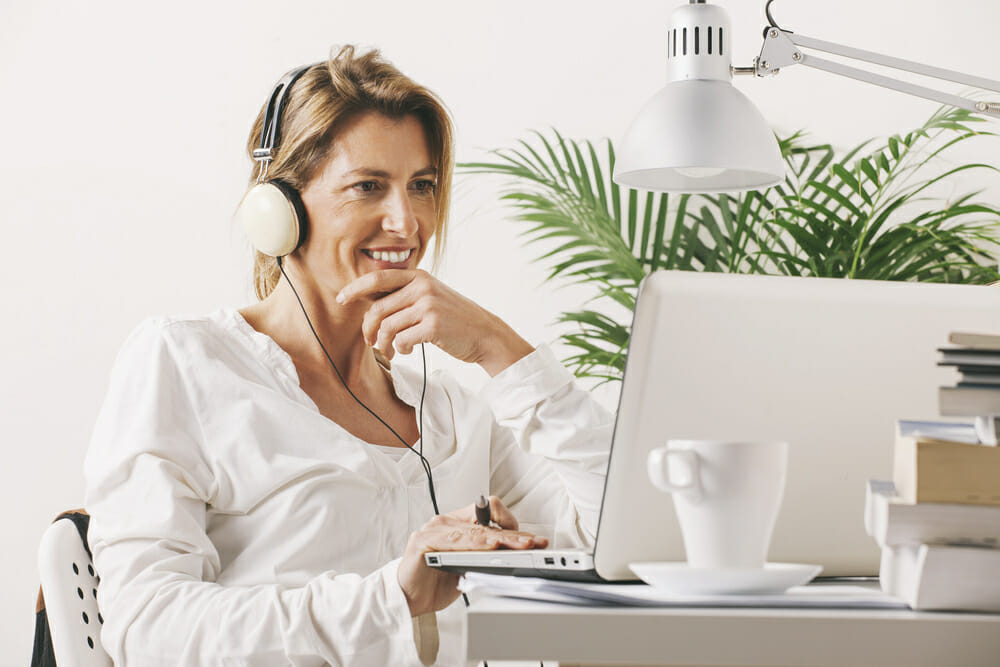 Woman with headphones on sitting in front of a laptop