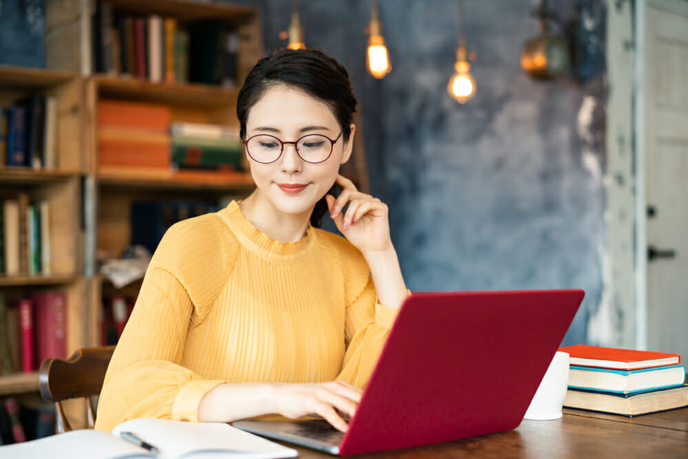 Woman sitting in a room with her laptop and books