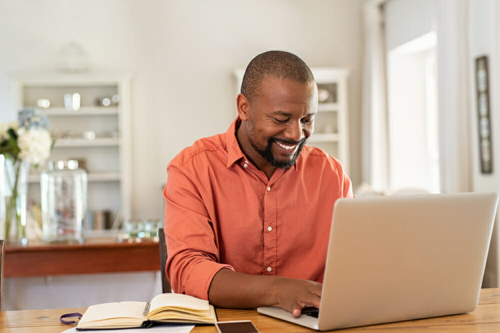 Man sitting in front of his laptop with a notebook