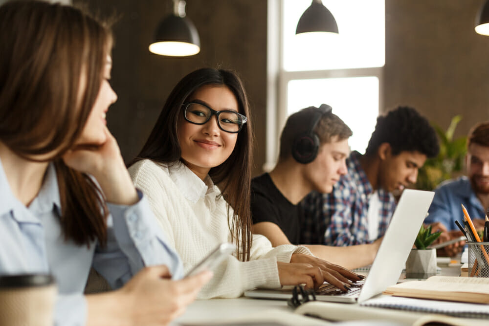 Students sitting at a table on their laptops