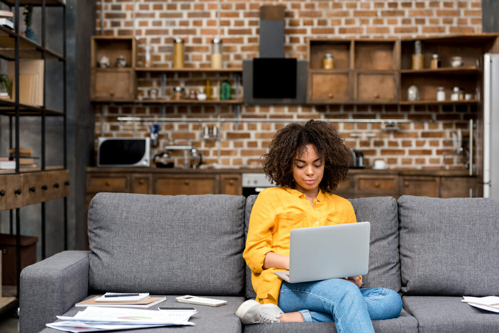 Woman working from home on her laptop sitting on the couch
