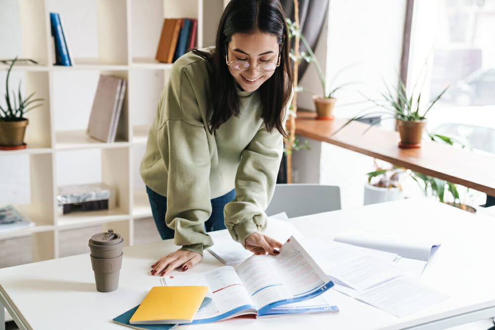 Woman standing over her desk looking at a notebook