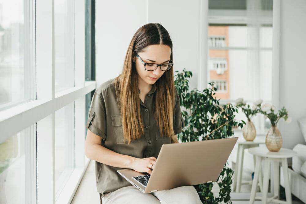 Woman sitting in front of a window with her laptop