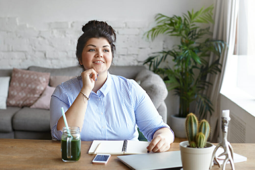 Woman sitting at a desk with a notebook and a drink