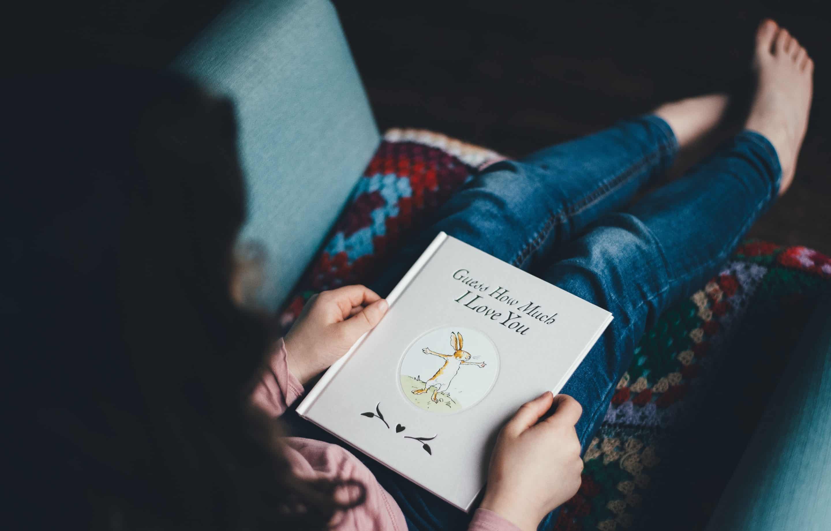 Woman sitting on a couch holding a children's book