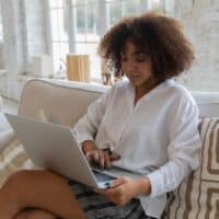 Woman sitting on a couch with her laptop.