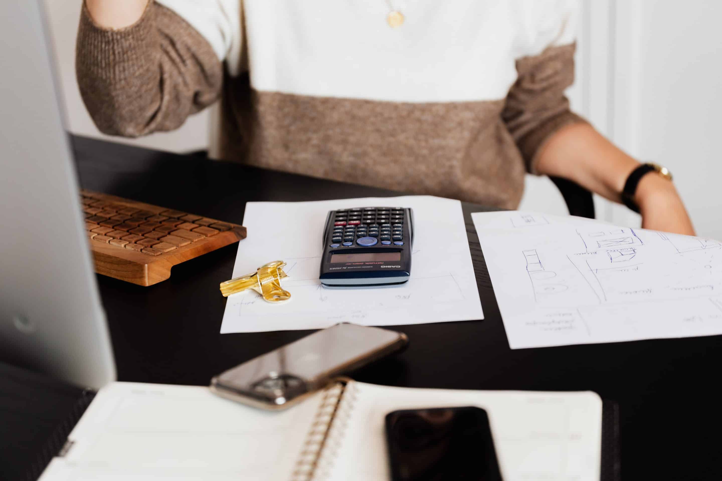 Woman sitting at a table with a calculator and notebook