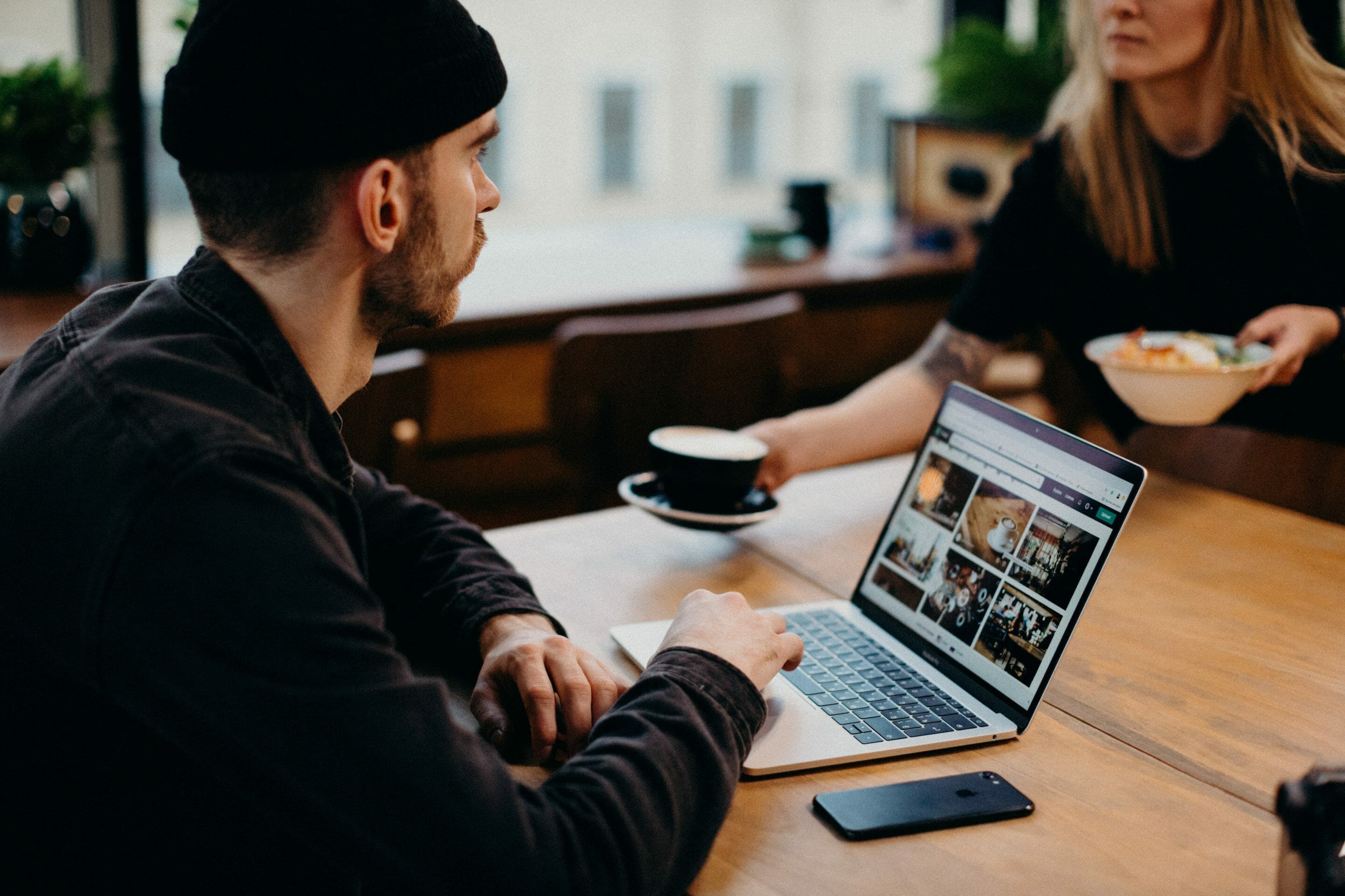 Man sitting at a table looking at Pexels.com with a woman sitting across from him holding a coffee mug