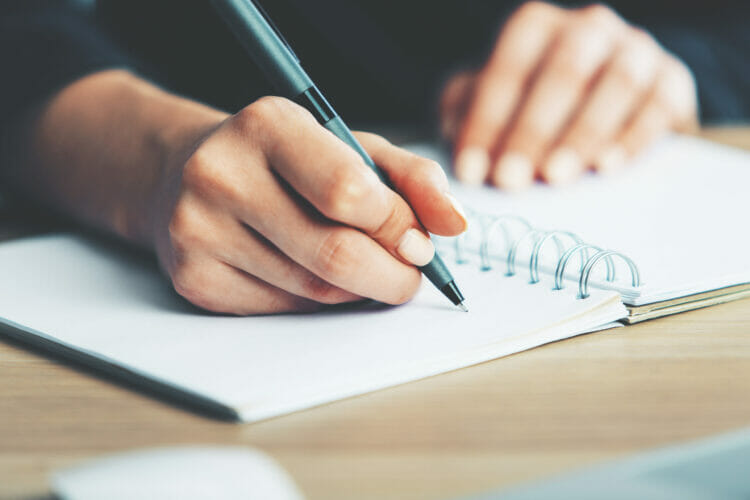 close up of woman's hand writing in notebook