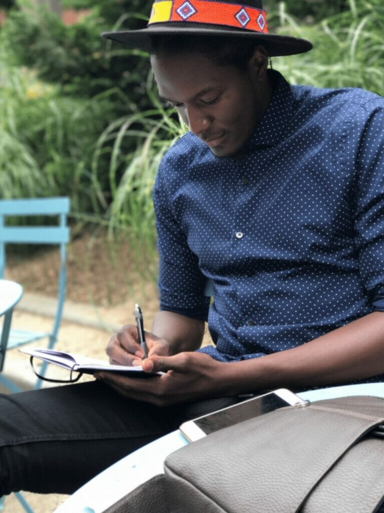 Photo of a young man writing with a pen in a notebook. He is concentrating on what he is writing. Maybe it's a submission planned to enter in a short stories contest or something similar